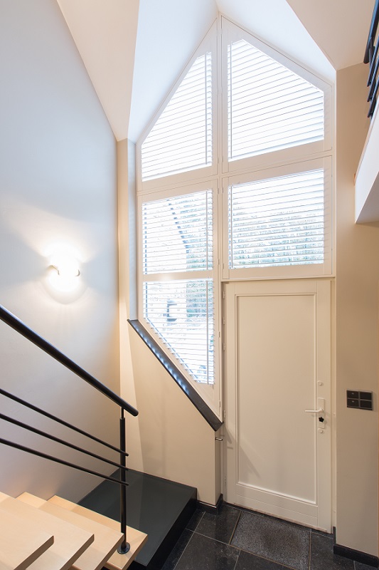 Schuin raam in de hal met shutters als raambekleding