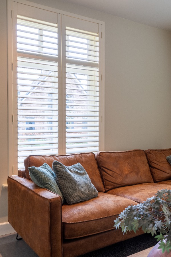 Woonkamer met offwhite shutters bij bank