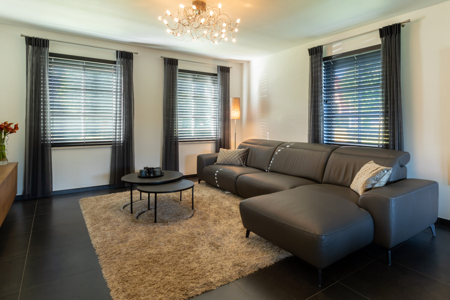 Woonkamer met daarin zowel gordijnen als shutters als raamdecoratie.